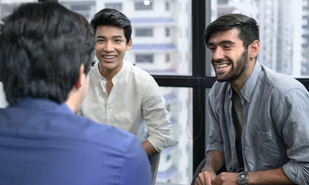 three men smiling while having a meeting