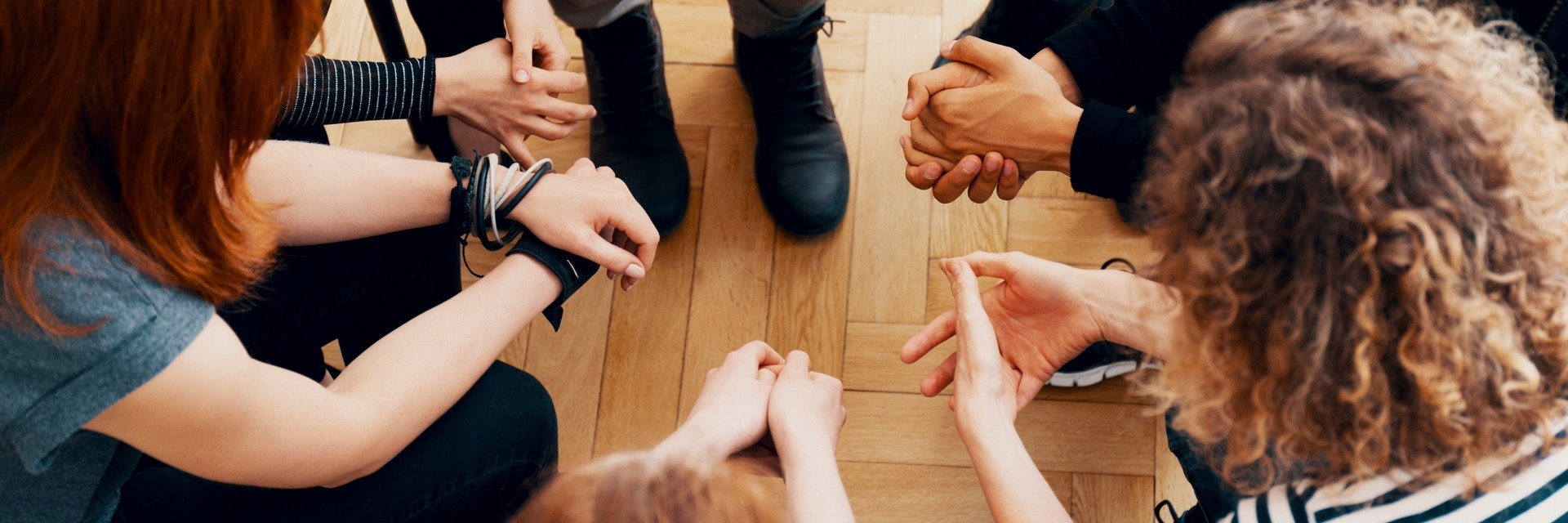 overhead view of hands of people sitting in a circle for group therapy