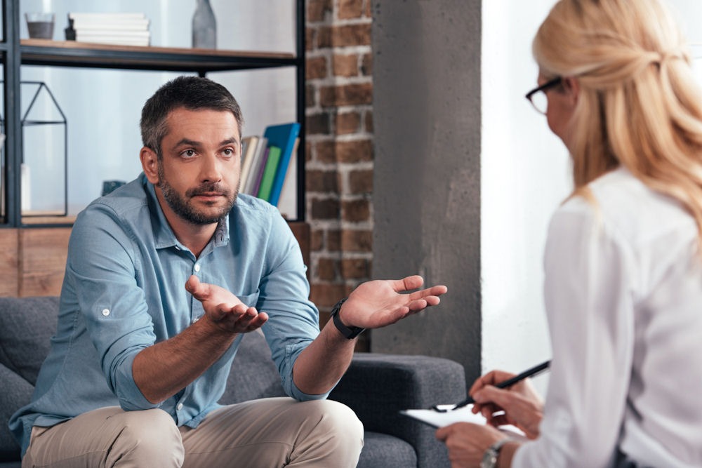 man sitting in therapy talking to therapist