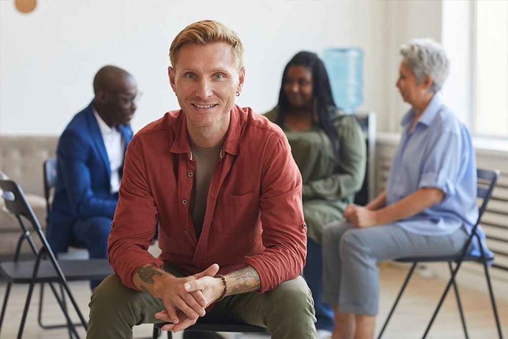 Smiling man in a group setting, discussing what Narcotics Anonymous offers for recovery