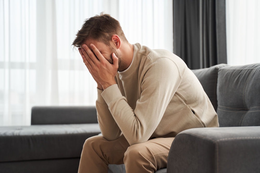 sad man covering his face and sitting