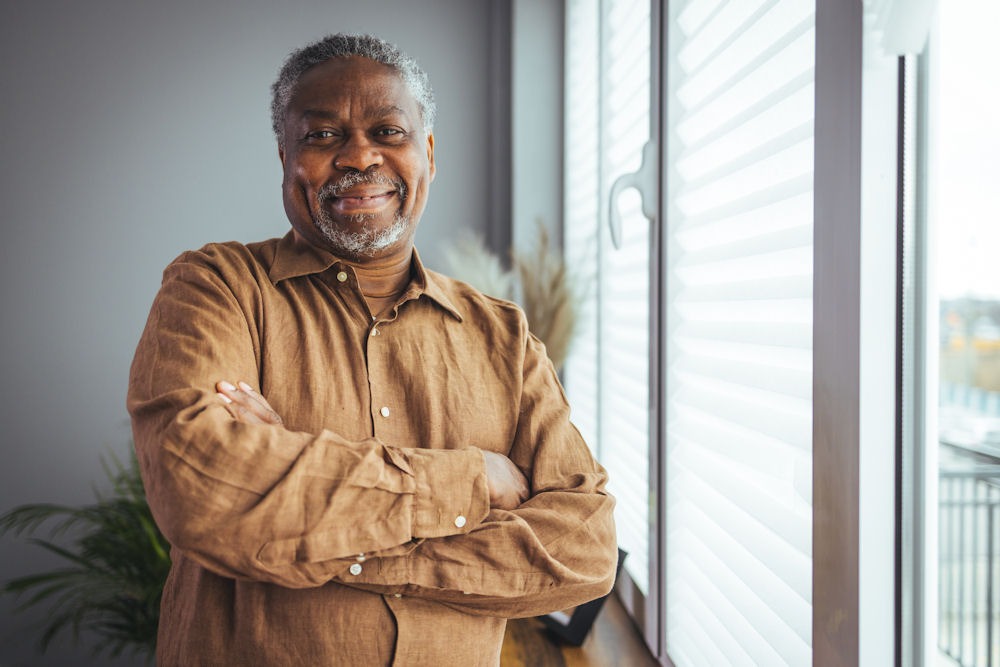 man standing by window smiling