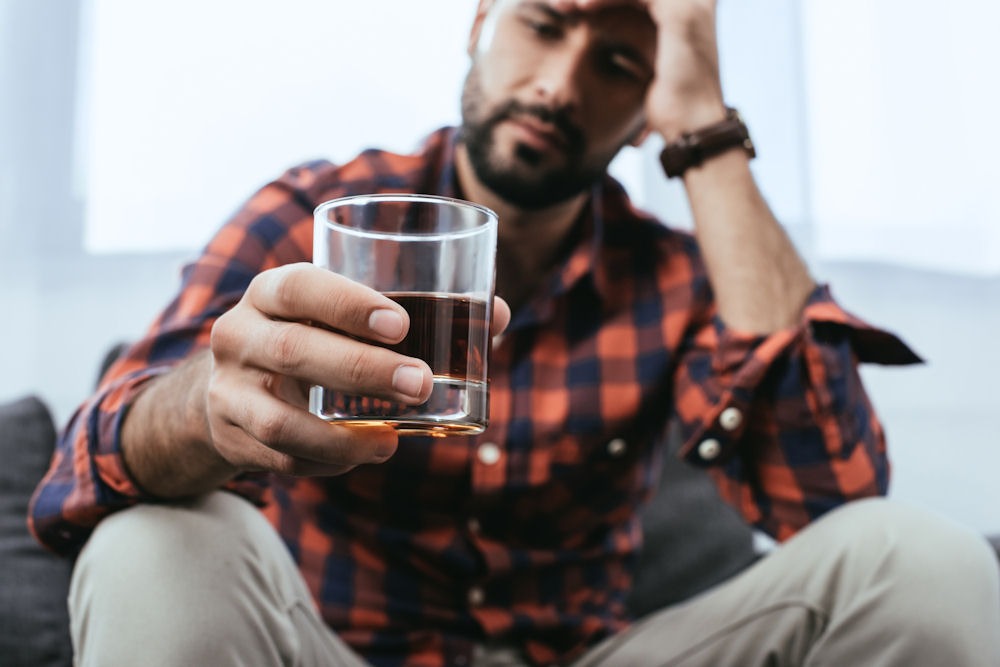 a-man-with-hand-on-head-holding-a-glass-of-beer