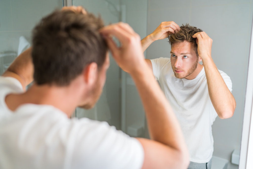 a-man-experiencing-hair-loss-looking-in-the-mirror