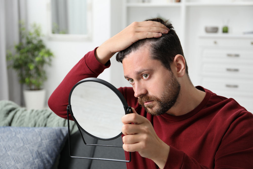 a-man-looking-in-the-mirror-experiencing-hair-loss